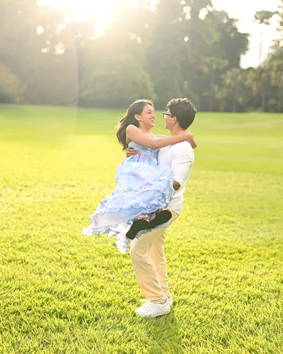 Devon lifting Nishara off the grass in golden light